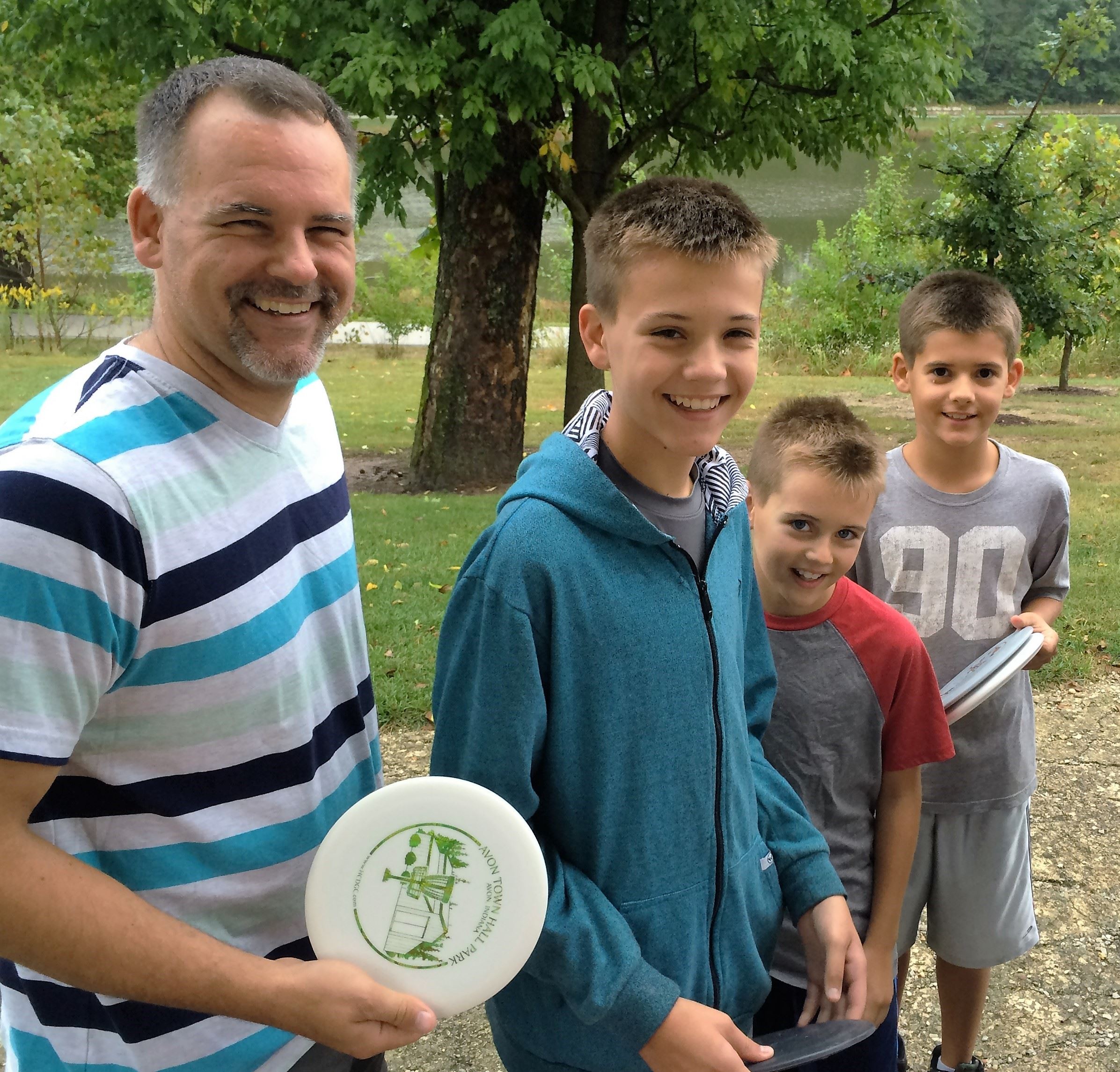 Man Holding Disc and Three Boys Smiling